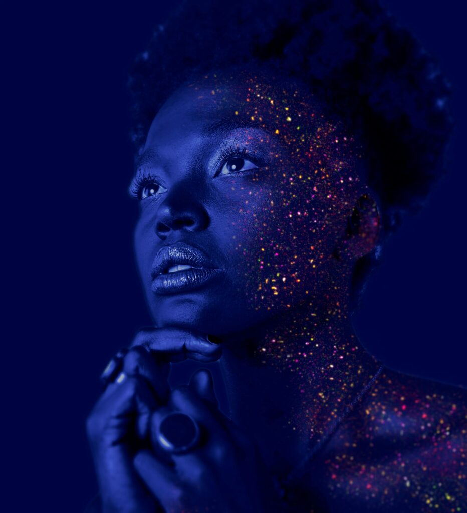 Mesmerizing portrait of a woman with glitter makeup and dramatic lighting.