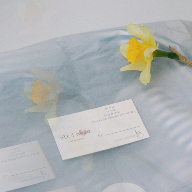 Delicate packaging with a daffodil and business cards under tissue paper, perfect for sophisticated branding.