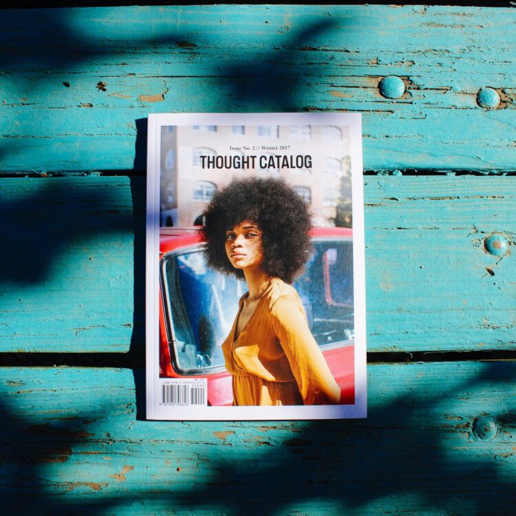 Thought Catalog magazine lies on a textured wooden surface, showcasing a stylish cover with vibrant shadows.