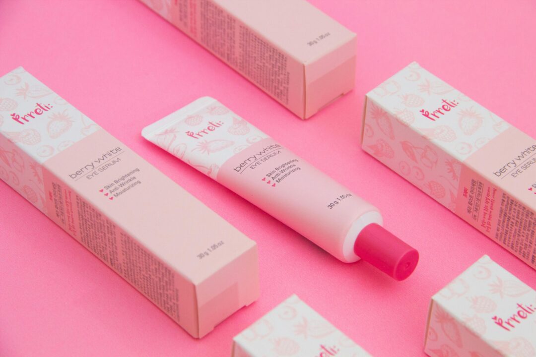 Pink-themed flat lay of berry-white eye serum with packaging.