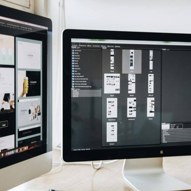 A modern workspace featuring dual computer monitors displaying web design projects, emphasizing technology and productivity.