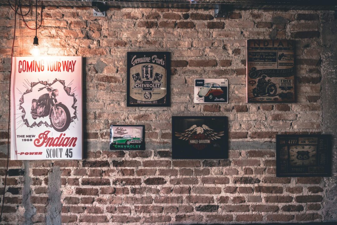 Retro wall art featuring motorcycle and car signs on a rustic brick wall.