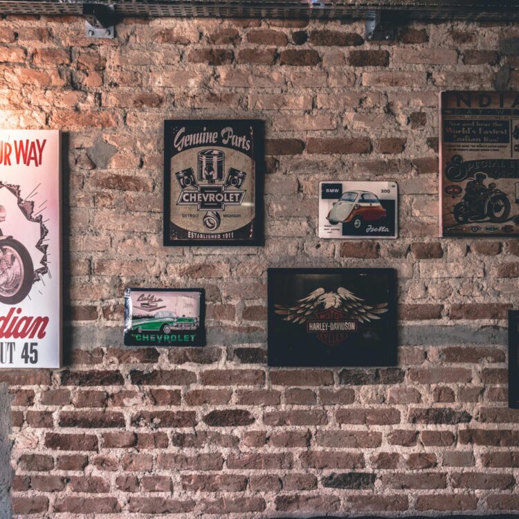 Retro wall art featuring motorcycle and car signs on a rustic brick wall.