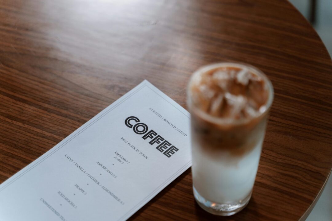 A refreshing iced coffee next to a menu on a wooden table, perfect for cafe vibes.