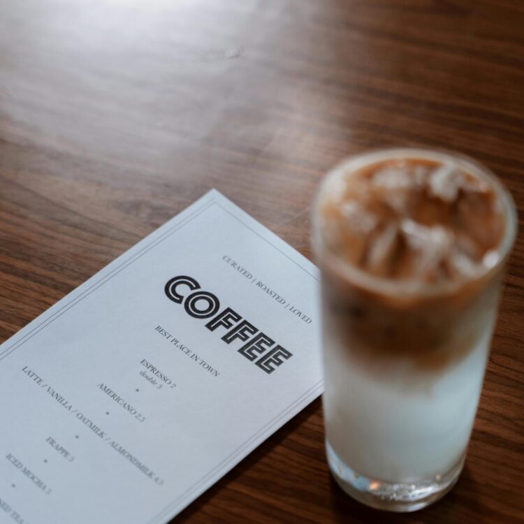 A refreshing iced coffee next to a menu on a wooden table, perfect for cafe vibes.