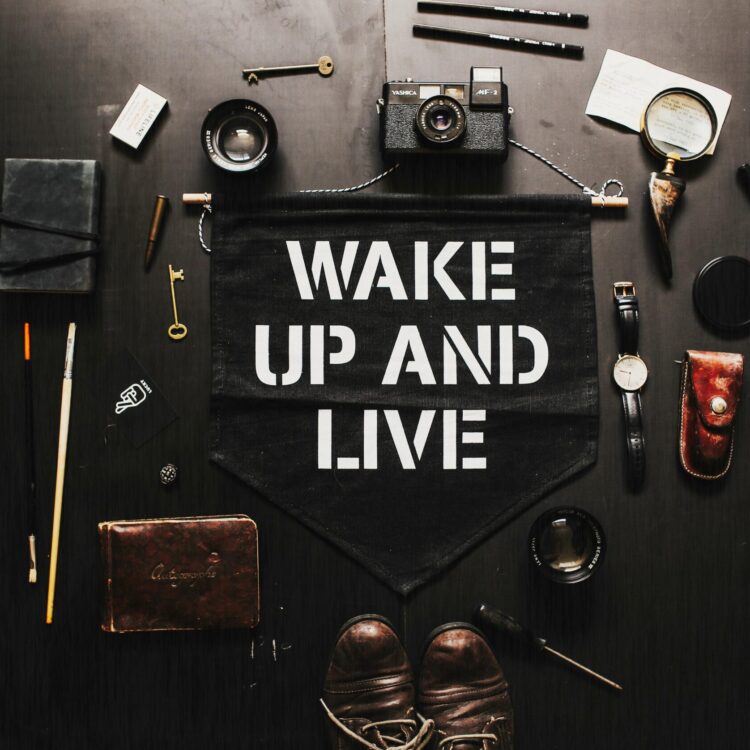 Flat lay of vintage tools, camera, and 'Wake Up and Live' banner. Inspiration for creativity.