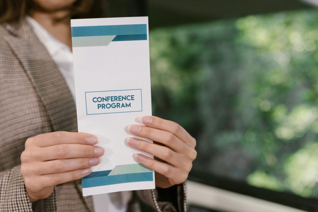 A professional holding a conference program brochure, ready for event attendees.