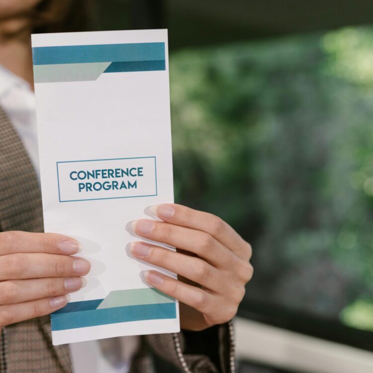 A professional holding a conference program brochure, ready for event attendees.